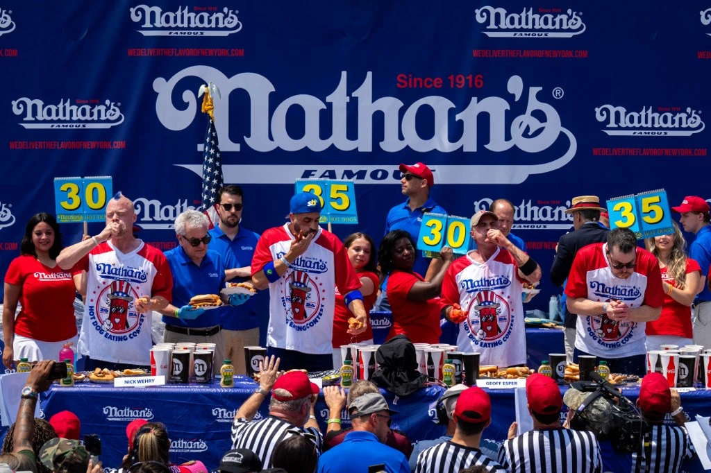 Participants compete for the mens title at Nathan's Annual Hot Dog Eating Contest on July 4, 2024 in New York City. Sixteen-time winner Joey Chestnut is banned from this year's contest due to his partnership with Nathan's competitor Impossible Foods, which sells plant-based hot dogs